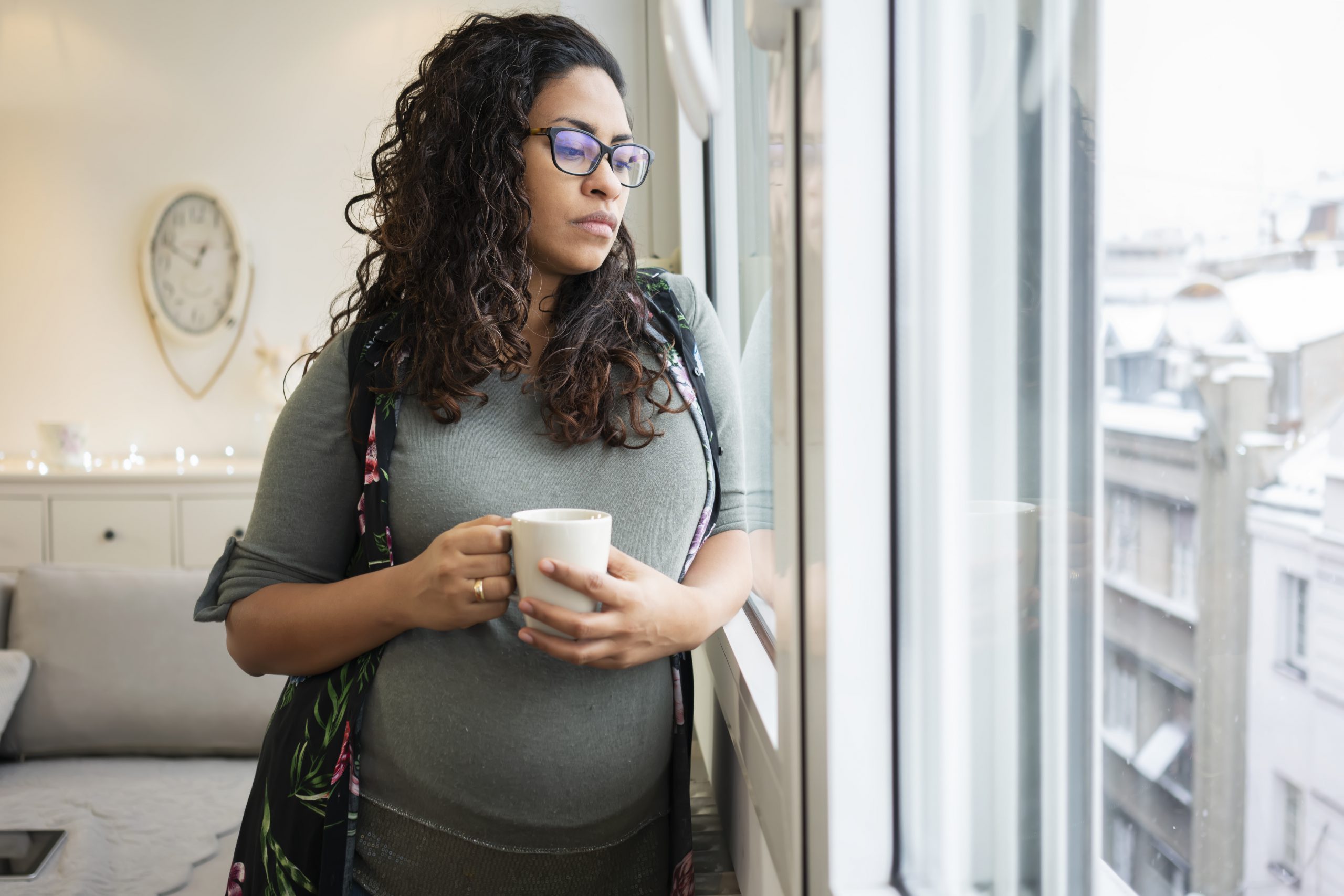 Pregnant woman drinking coffee at home